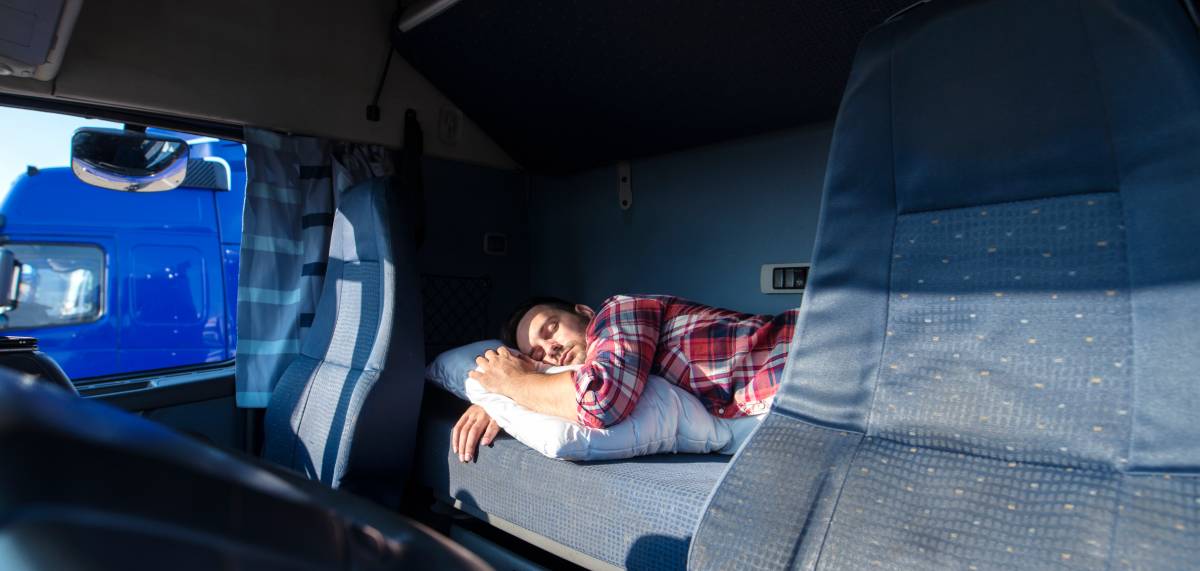 Professional truck driver resting inside a semi-truck sleeper cab